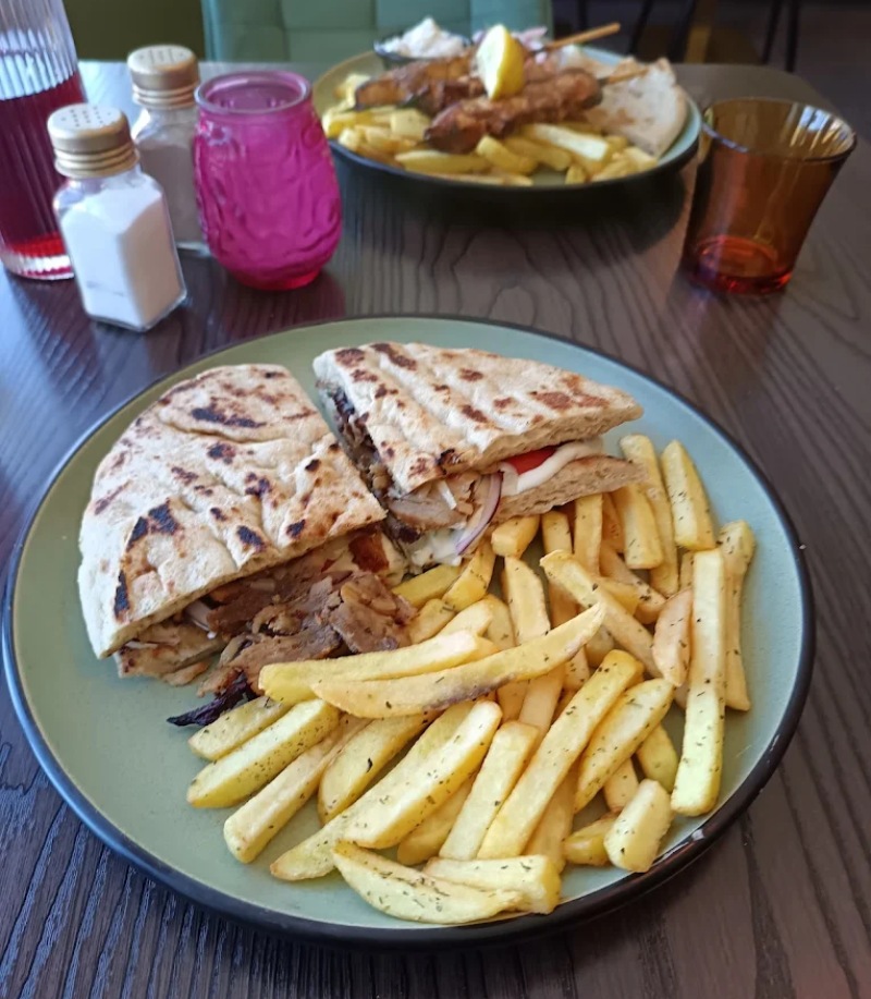 Gyros wrap cut in half with a side of seasoned french fries, served on a light green 
plate at Greek Theory Restaurant in Falkirk