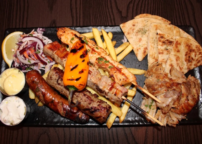 Ultimate platter with BBQ ribs, wings, loaded fries, halloumi, and fresh salad 
served in Greek Theory, Falkirk. 